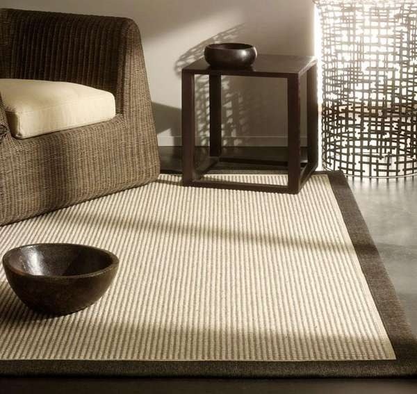 Alfombra Maori de Tasibel en ambiente residencial de alta gama: mezcla sisal-lana, ribete en contraste, textura téxtil natural mate